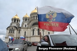 Женщина машет российским флагом из машины во время первомайского митинга в городе Новочеркасске Ростовской области. Россия, 1 мая 2023 года.