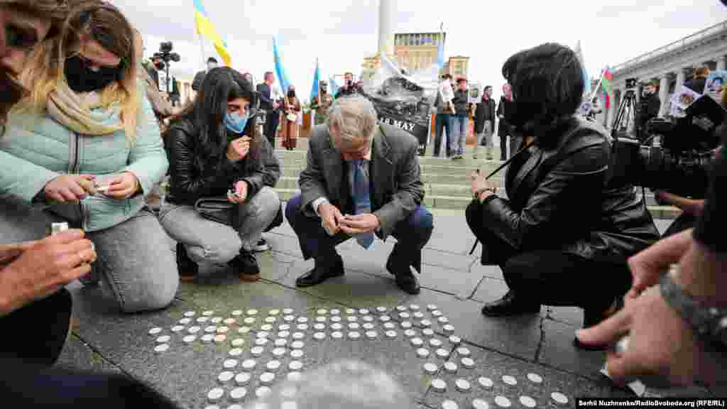 Лидер крымскотатарского народа Мустафа Джемилев зажигает свечи в виде тамги &ndash; национального символа крымских татар. Участники акции также принесли с собой портреты арестованных и осужденных российскими судами крымских татар