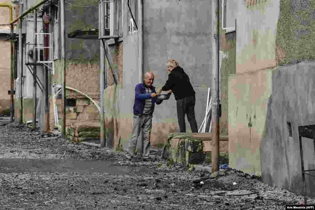 Соседи делятся едой возле разрушенного жилого дома в Степанакерте, 8 октября